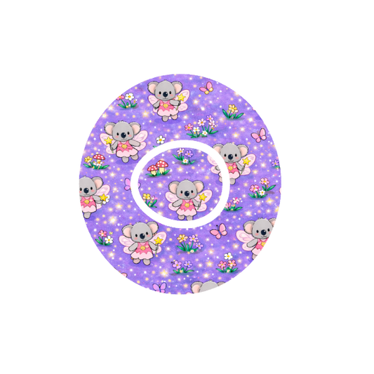 Circular shape with Binki the koala dressed as a fairy playing in a fairy garden  with mushrooms and flowers with a lilac background fits CGMDexcom One+ and G7 device.