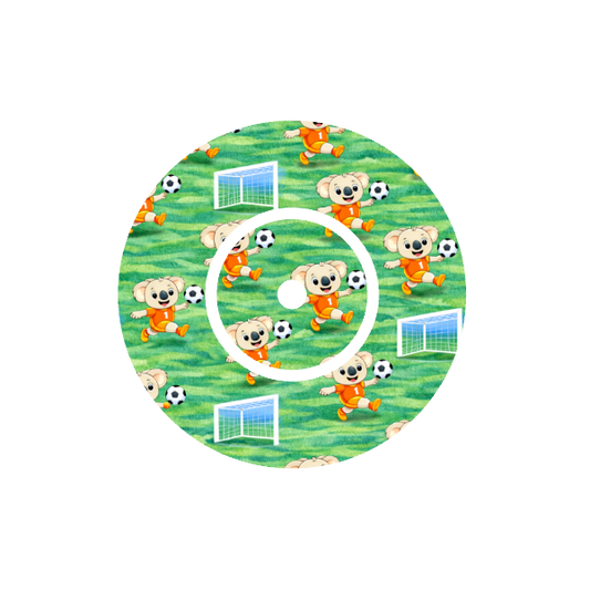 Circular design with animated Binki the koala playing soccer on a green soccer field fits CGM Dexcom One+ and G7 device.