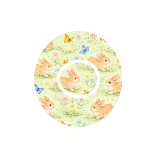 Circular shape soft animated Bunnies playing with butterflies in a meadow of flowers with a cream background fits CGM Dexcom One+ and G7 device.