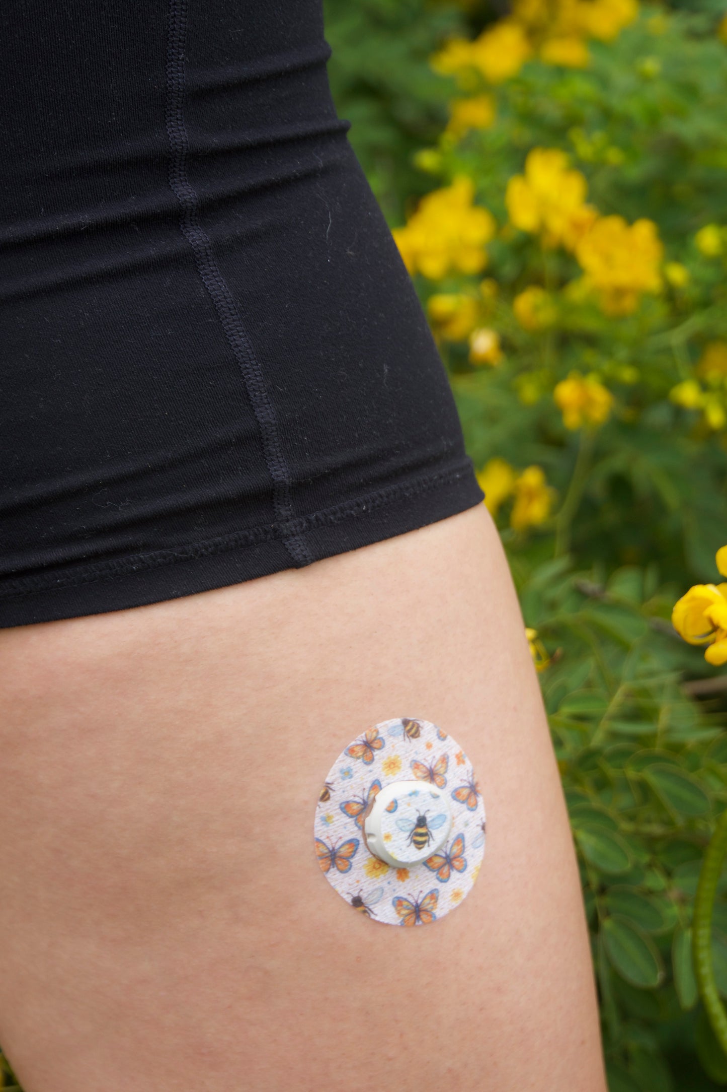 Bees and Butterflies CGM patch for Dexcom G7 — bees and butterflies with flowers on off white. Upper leg.