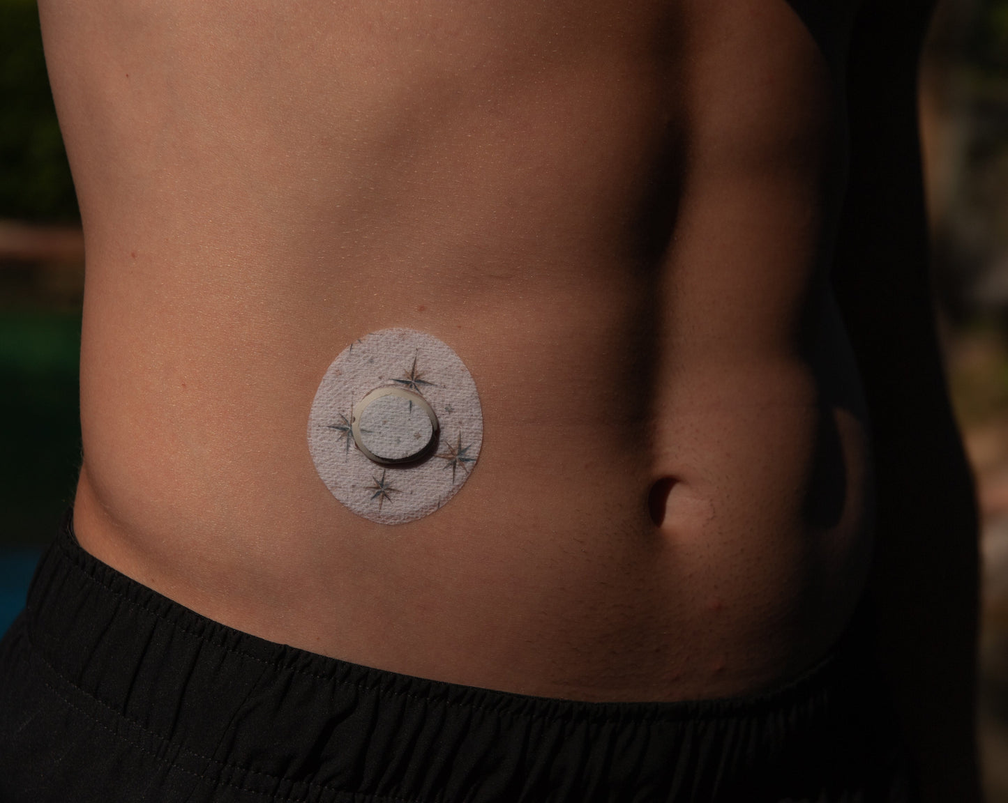 CGM patch on abdominals .  compass with starburst on taupe background. Device Dexcom G7 device.