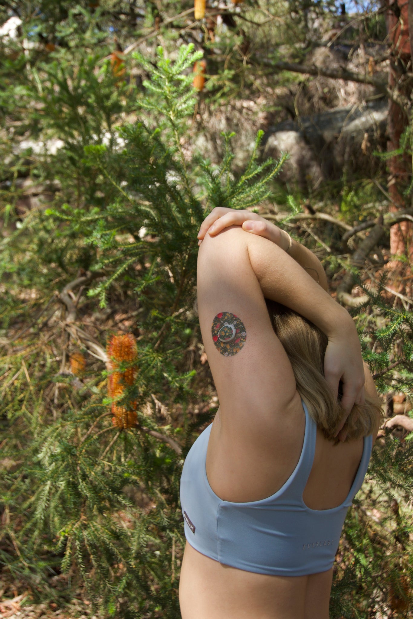 CGM patch on upper body upper arm . Australian native florals on green background Device Dexcom G7 device.